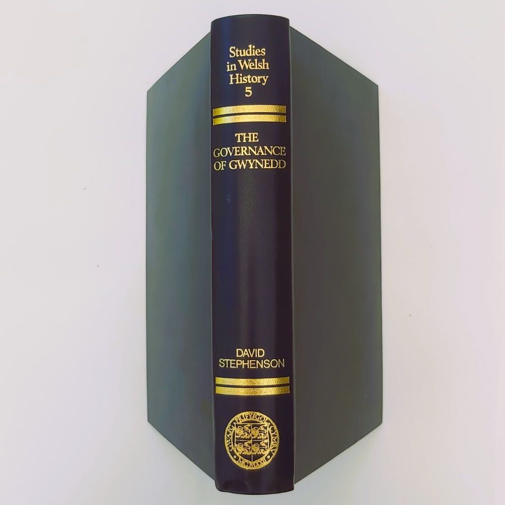 Governance of Gwynedd Close-up view of the spine of the book bound in dark blue cloth, showcasing vibrant gilt-stamped lettering for the title, author, series number 5, and the University of Wales crest Stephenson (3)a