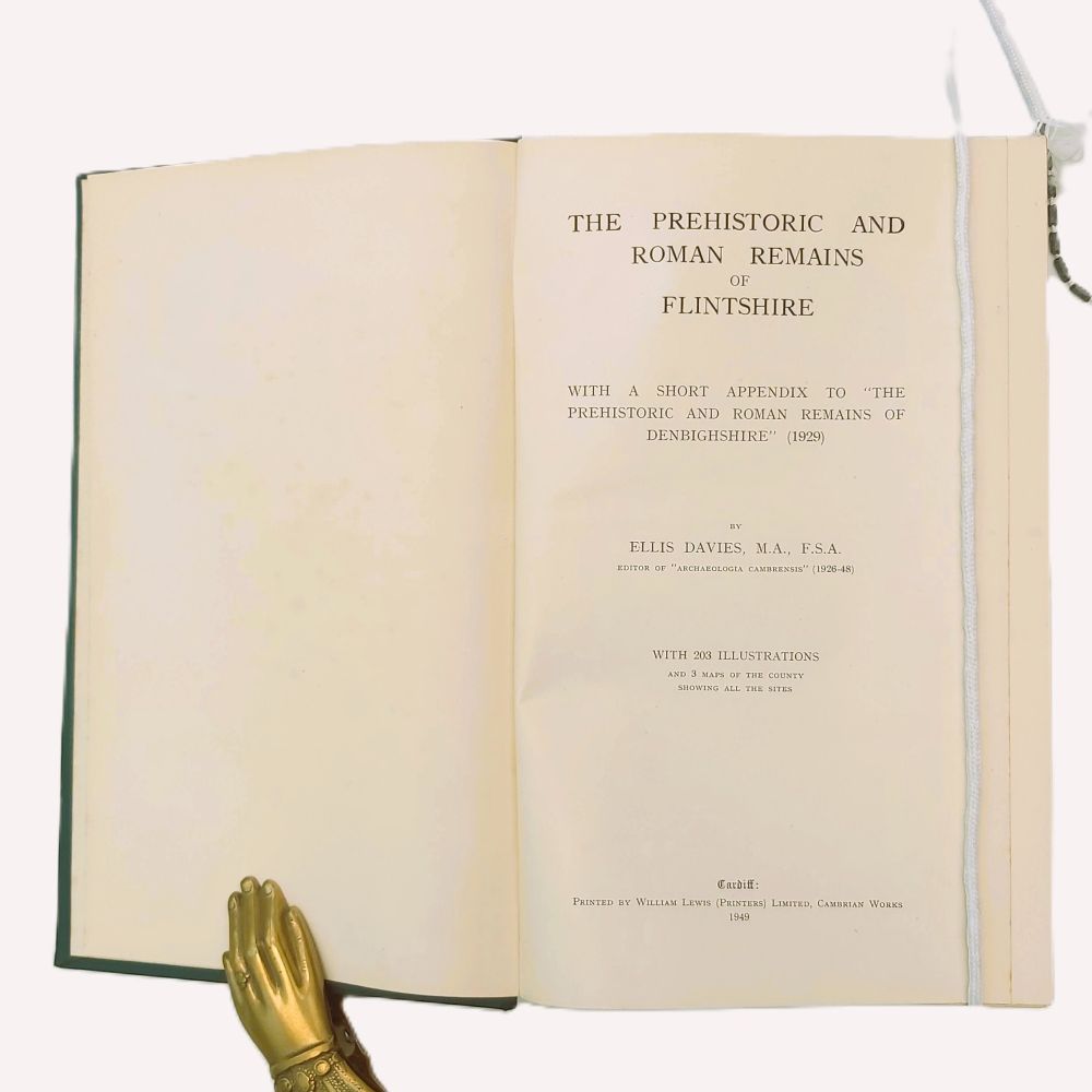 Prehistoric and Roman Remains of Flintshire Davies (5)a Open title page of the 1949 book "The Prehistoric and Roman Remains of Flintshire" by Ellis Davies, detailing 203 illustrations and 3 maps, held open by a decorative brass hand weight.