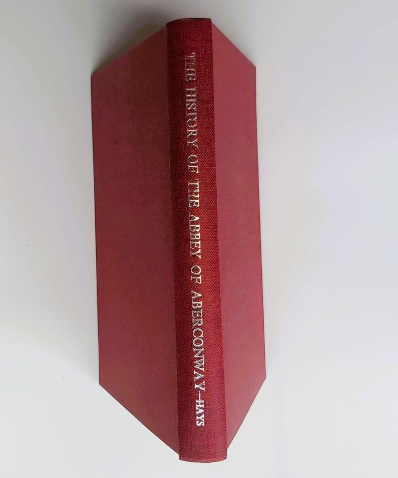 History of the Abbey of Aberconwway Hays (3) Standing spine view of a hardback book bound in textured red cloth, showcasing crisp silver-stamped typography for the title, author surname, and decorative rule markers.